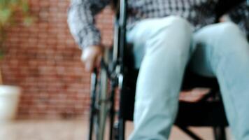 Close-up view from below a guy, disabled person with a lesion of the spinal cord and legs, multiple sclerosis, in a wheelchair enters the frame, home environment, indoor. video