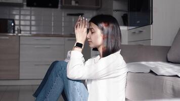 Unhappy young woman sitting in the kitchen at home and touching her hair with her hands after a hard work day. Concept of tiredness and exhaustion video