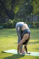 Indian Female Yoga Instructor Doing Standing Forward Bend Pose photo