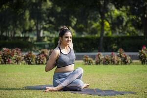 Female fitness trainer performing Gomukhasana asana in park. photo