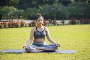 Healthy Female Sitting In Lotus Position In The Park. photo