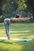 Fitness Expert Performing Half Standing Forward Bend Yoga In Park. photo