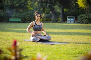 A Confident Woman Sitting in Agnistambhasana pose in tha park photo