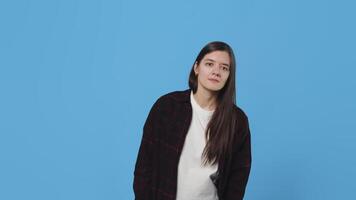 Young attractive woman looking into the distance, recognizing something and then becomes happy and jumping for joy on a blue background in a studio video