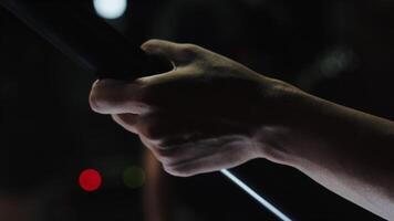 Close-up of the hand of a guitarist who moving his fingers on a fretboard and playing different chords during the show on a stage with concert light video