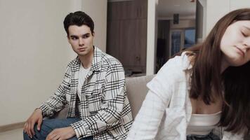 Offended young caucasian woman sitting on the couch back to young caucasian man who trying to apologize, but she refuses it. Concept of problems in couple relationship video