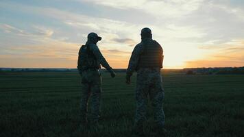 crépuscule poing bosse. soldats geste de unité, deux soldats partager une poing bosse dans le champ, uni contre une crépuscule ciel toile de fond. video