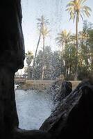 look through a whole in the rocks through the waterfall on the trees photo