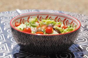 green salad with Cherry tomatoes, olives, onion, fresh herbs, lemon juice and olive oil photo