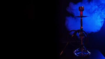 hookah with a glass flask with hot coals in a bowl on the table with blue smoke video