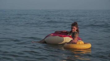 mujer mamá con un san chico nadar en el mar en inflable círculos en el verano video