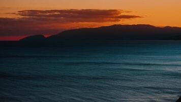 timelapse of a dramatic orange sunset over the sea with mountains video