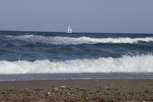 sailboat at sea, waves on the coast photo