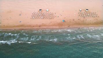 antenne visie van sereen zonsopkomst over- zanderig strand met golven in kust- stad- video