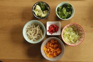 ingredients to cook asian soup, bean sprouts, carrots, cabbage, chili pepper, lime, coriander photo