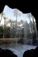 look through a whole in the rocks through the waterfall on the trees photo