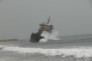 shipwreck against which the waves crash, cotonou, benin photo