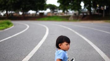 Little boy sitting on running track in a stadium. video