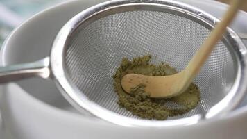 Close up and Slow Motion Footage of Small Spoon Sifting Matcha Powder through Fine Tea Sieve. Green Tea Ceremony video