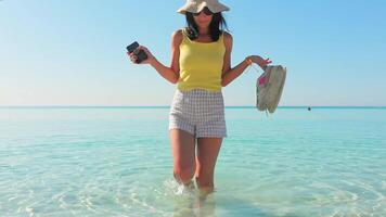 ragazza gambe a piedi su acqua onde sottile femmina gambe mossa su lungomare spruzzo di acqua vacanza su spiaggia nel lento movimento Perfetto donna gambe con gioia su riva del mare godere estate vacanza video