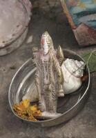 plate with offer items, statue, shell and flowers, hindi, varanasi, india photo