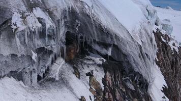 uma sereno e pitoresco inverno panorama apresentando coberto de neve montanhas com pingentes de gelo suspensão a partir de a lados e uma congeladas cascata. aéreo Visualizações capturar a beleza do a gelado cenário video