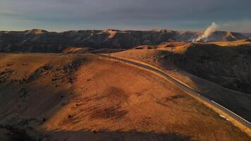 Road traversing desert with mountains in distance, under clear sky video