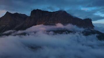 montaña envuelto por nubes en contra un sereno azul cielo video