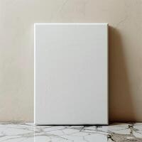 A blank canvas sits on a marble table against a beige background. photo
