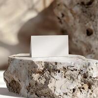 A minimal mockup of a blank folded card on a rough stone podium against a blurred background. photo