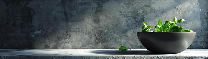 A dark bowl sits on a concrete table against a dark background. The bowl is filled with fresh green basil. photo