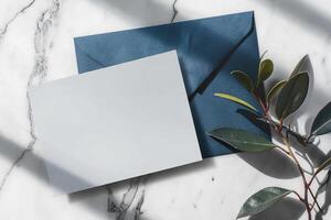 Blue and white marble table with a blank note and a blue envelope next to a plant photo