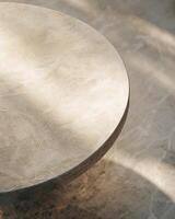 An image of a round marble table with a smooth surface and sunlight reflecting on it. photo