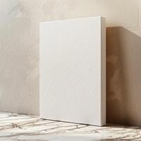 A blank canvas stands on the marble floor, leaning against a beige concrete wall with a subtle striped texture. photo