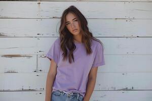 A beautiful girl with long brown hair wearing a purple t-shirt and blue jeans is standing in front of a white wooden wall. photo