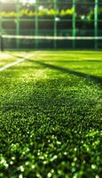 Close-up of green tennis court with white lines and net in the background photo