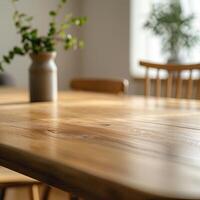 An empty wooden table with a vase of eucalyptus leaves in the background photo