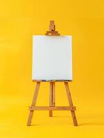 Blank canvas on wooden easel isolated on yellow background. Artistic concept. photo