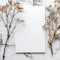 Blank white paper card mockup with dry twigs on marble background. Flat lay, top view, copy space. photo