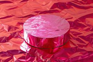 A pink metallic cylinder sits on a matching pink surface. photo