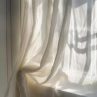 white curtain blowing in the wind. The light from the window is shining through the curtain. The curtain is made of a soft, lightweight fabric. photo