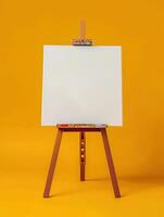 Blank canvas on wooden tripod isolated on yellow background. Artistic concept with copy space. photo