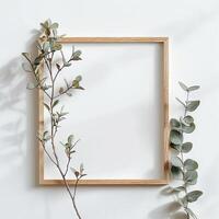 Minimalist still life photography of a blank wooden frame with seeded eucalyptus. photo