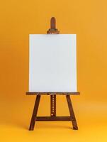 Blank canvas on wooden easel isolated on orange background. photo