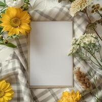 A blank note surrounded by a variety of yellow and white flowers on a gray and white checkered tablecloth. photo