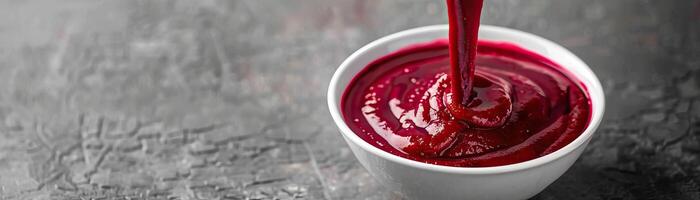 A dynamic angle capturing the moment of pouring a vibrant beetroot cream soup into a bowl, the color and motion in focus, set against a clean, minimalist background, wide space on photo