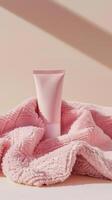 a tube of body cream sitting inside of a pink towel photo