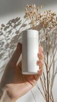 closeup of woman s hand holding a white roll on deodorant bottle photo