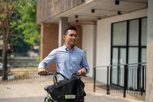 A happy, carefree Asian businessman going to work with his bicycle on a sunny day. photo