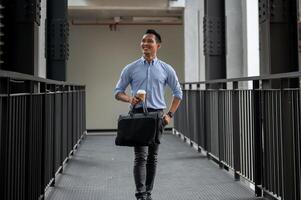 A handsome and confident Asian millennial businessman walking along the building corridor. photo